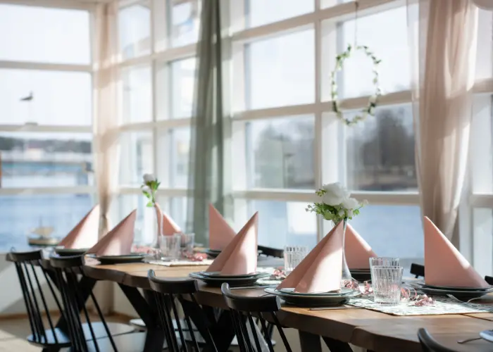 Katettu juhlapöytä Seelarin ravintolassa Oulussa, suuret ikkunat ja merimaisema taustalla